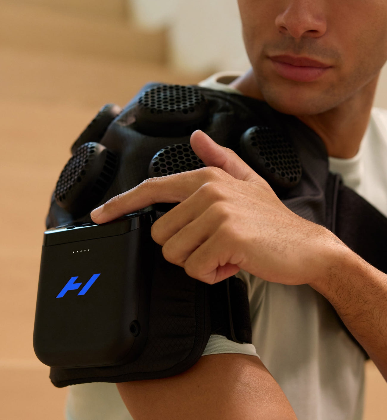 اللقطة الجانبية لشخص يضبط وحدة التحكم في جهاز Hyperice X 2 للكتف